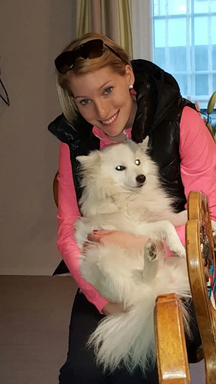 Junge Frau mit einem weissen Spitz auf dem Arm