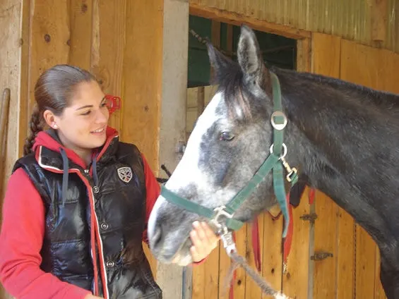 Junge Frau mit ihrem Pferd im Stall